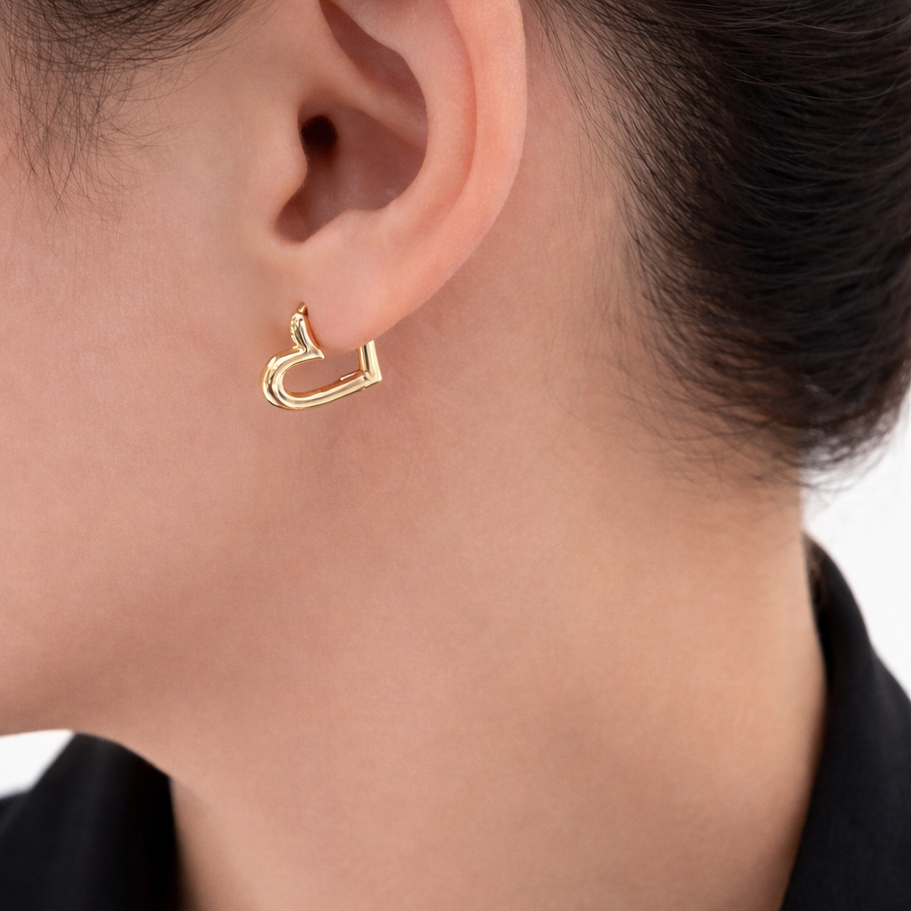 A woman earings heart shaped earring hoops made from 18k gold vermeil